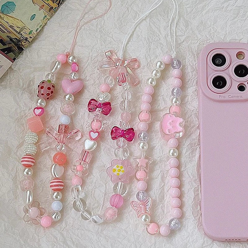 Sweet strawberry flower bead phone strap charm with pink beads and a small flower pendant, attached to a cellphone lanyard.